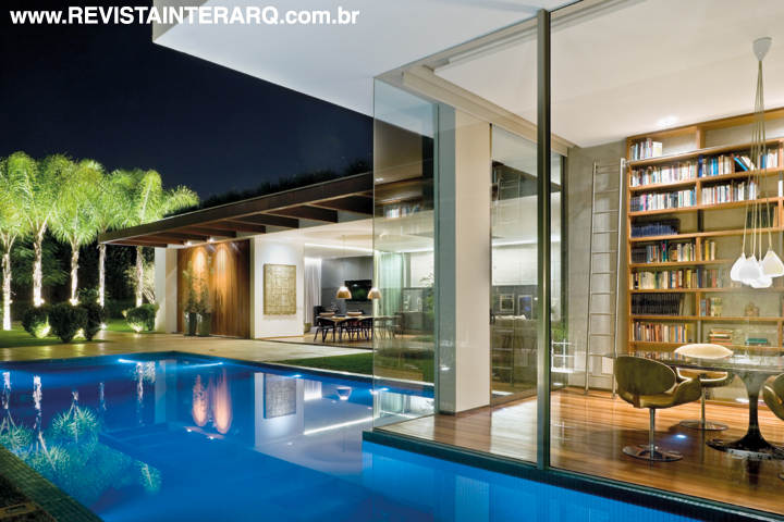 Panos de vidro deixam o office à beira d’água. Sobre a mesa Saarinen com tampo em mármore Nero Marquina, pendente com cúpulas brancas