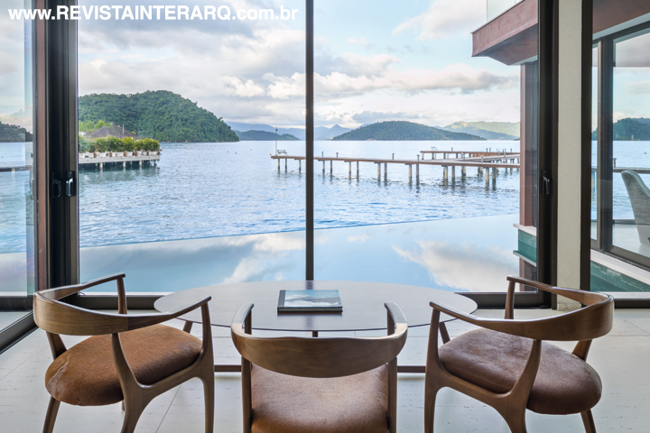 um ambiente com mesa baixa e cadeiras convida a admirar as ilhotas que pontuam a paisagem