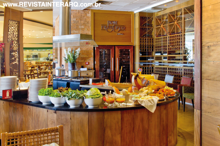 O mobiliário planejado em madeira e as paredes em tijolinhos favorecem a atmosfera receptiva do restaurante. Para acomodar os alimentos, foi criada uma bancada em granito preto (Marmoraria Alvorada) e madeira