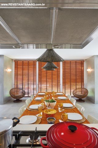A cozinha mereceu atenção especial por ser o ponto de encontro da família. Integrada à varanda, tem ilha central revestida com pastilhas amarelas (Casa dos Construtores) e bancadas em Silestone. A coifa é da Refrigeração Araçatuba. A foto maior exibe as belas persianas de madeira e cadeiras da Jackie Móveis. Iluminação técnica da Ataluz