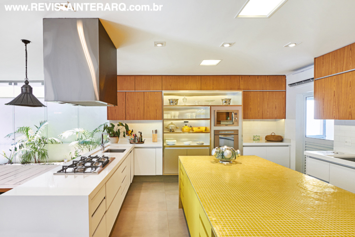 A cozinha mereceu atenção especial por ser o ponto de encontro da família. Integrada à varanda, tem ilha central revestida com pastilhas amarelas (Casa dos Construtores) e bancadas em Silestone. A coifa é da Refrigeração Araçatuba. A foto maior exibe as belas persianas de madeira e cadeiras da Jackie Móveis. Iluminação técnica da Ataluz