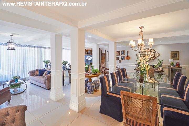 A eliminação de algumas paredes unificou o espaço social, setorizado apenas por móveis e acessórios. Boiseries nas paredes e nos pilares estruturais se unem aos lustres de estilo (Frontier) para evocar a aura clássica. Os estofados e as cortinas neutros ressaltam as almofadas em tons sóbrios e acompanham a paleta dos garden seats e outros objetos decorativos. O piso em porcelanato é da Casa dos Construtores