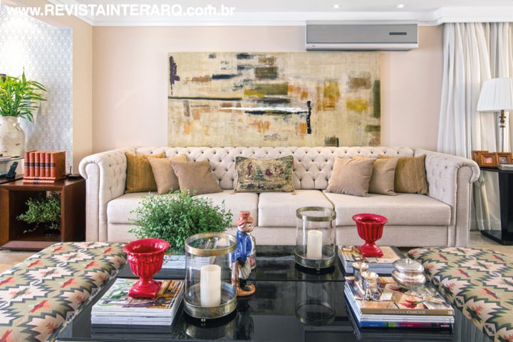 Detalhe do estar, com sofá em capitonê, pufes estampados e mesa em laca preta