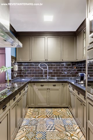 A cozinha aberta para a sala, estilo americano, aumenta a ala social. Os azulejos pretos e os armários cinzas acompanham a paleta dos ladrilhos hidráulicos do piso. Todos os revestimentos são da Casa dos Construtores