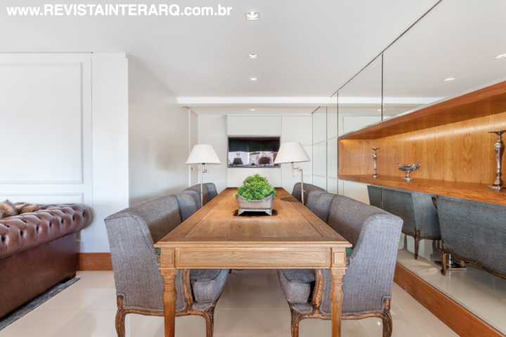 A sala de jantar tem bancos estofados no lugar das cadeiras e mesa de madeira de demolição