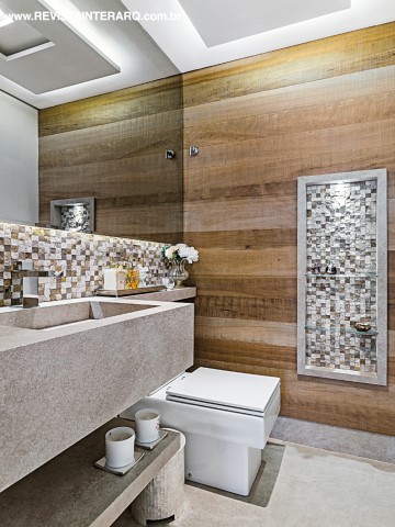 Aconchego do lavabo foi definido pelo mix de madeira na parede e os detalhes em pastilhas. A bancada é em Porcelanato italiano Infinity Stone Natural bege, o mesmo utilizado no piso do apartamento, executada pela Di Pietra Porcelanatos
