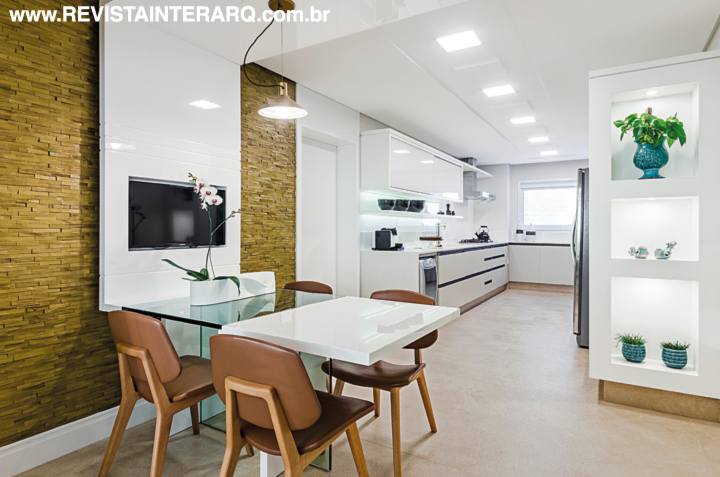 Durante a reforma, a arquiteta nivelou o piso da cozinha com o da varanda e integrou as áreas, setorizadas somente pela mesa de vidro e laca branca da copa. O destaque ficou para a parede com revestimento de madeira, que emoldura o painel em laca branca alto brilho. Móveis projetados pelo Okha e executados pela France Decor