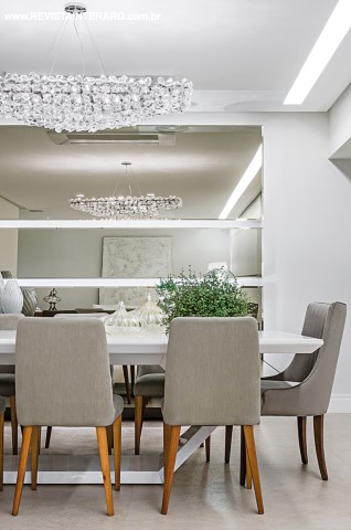 A grande estrela da sala de jantar é o pendente de cristais Flora. Ao fundo, espelho desenhado pela arquiteta com bordas bisotadas e acabamento bronze. O projeto foi todo automatizado pela Integra Mídia