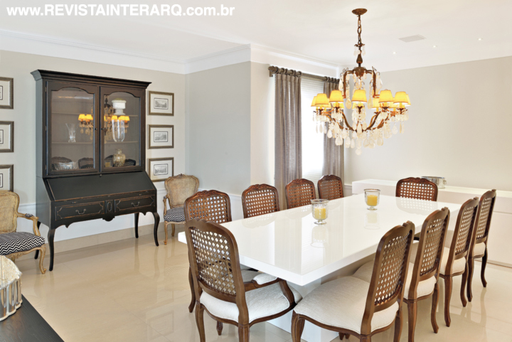 O jantar conta com mesa em laca branca e cadeiras com encosto de palhinha (tudo da Robuste) sob o lustre de cristais de rocha (Luminá Ribervent)