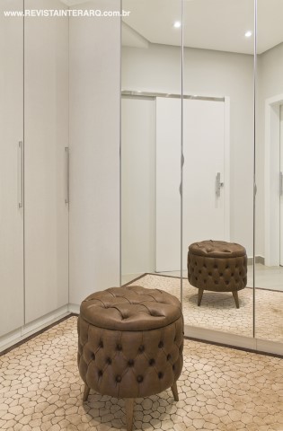 Espelhos e armários brancos (Romanzza) conferiram leveza ao closet, com tapete em couro e pufe em capitonê (ambos da P.O. Móveis e Estofados)