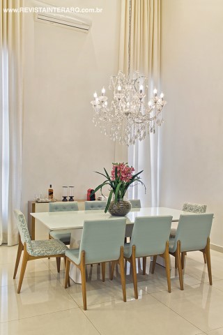 O lustre de cristais (Casa Luz) acompanha o pé-direito nas alturas da agradável sala de jantar, decorada com aparador, poltronas estofadas e mesa em laca branca. Cortinas em linho (Everson Pasqualatto) suavizam a luz do sol. No piso, porcelanato da Casa dos Construtores