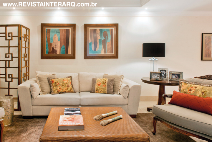 No alto, o living com sofá, poltrona e mesa da UneRobusti e mesas laterais Sierra UneRobusti sobre o tapete estonado da Bidjar ganhou um ar luxuoso. Nas paredes, a cascata de luz projetada pela Luminá Iluminação foi embutida no forro de gesso