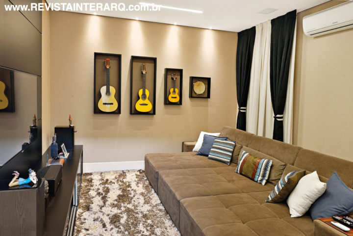 No home theater, as molduras destacam os instrumentos musicais, que podem ser facilmente retirados para serem tocados. As paredes revestidas com palha (Casa Ville), as cortinas e o tapete felpudo se unem ao amplo sofá com chaises para evocar conforto. Estante da Florense