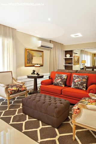 O living tem a delicadeza das almofadas florais com o sofá vermelho e as poltronas de estilo (tudo da ACB Casa) sobre o tapete neutro (Bidjar Tapetes). Objetos de decoração da Casa Verão e piso da Portobello Shop