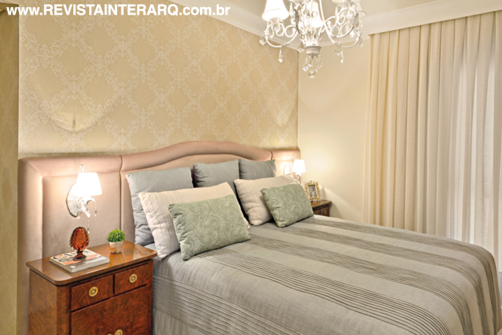 A suíte evoca o relaxamento com papel de parede, enxoval e cortinas suaves (ACB Casa), lustre romântico (Luminá Iluminação) e móveis elegantes da Artefacto (UneRobusti)