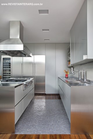 O mosaico de pastilhas de vidro delimita a área molhada da cozinha com ilha e bancada em inox