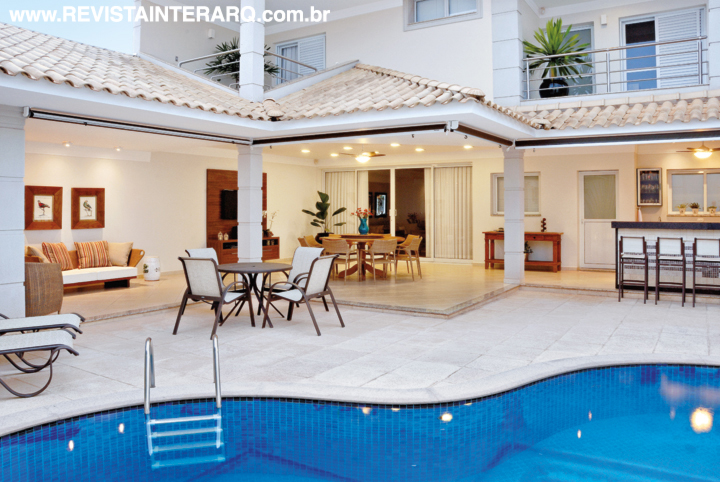 Os acessórios são da Casa Verão. Na foto maior, o piso da Castelatto reveste o entorno da piscina em pastilhas e borda de mármore Travertino jateado. Na área da churrasqueira, o piso da Portobello Shop recebe a mesa da MAC Móveis e cadeiras e banquetas da Copav. O aparador é da UneRobusti. Iluminação da Luminá Iluminação
