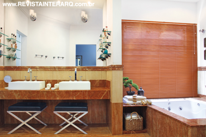 O banho do casal chama a atenção pelo trabalho em mármore Crema Marfil e mármore Coralito Espanhol (Marmoraria Exclusive). Louças Deca da Duo. Banquetas em inox da UneRobusti