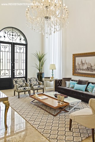 A beleza da porta de entrada em ferro trabalhado permite a abundância de luz natural no living. O lustre de cristal acompanha o décor com móveis da Decorativa e cortina da Decora Móveis. Os acessórios decorativos são da Krieê Decorações 
