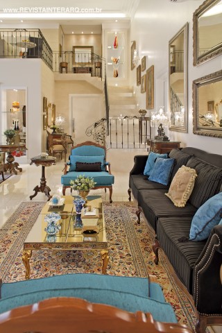A iluminação embutida e direcionada (Ataluz) ressalta a decoração elaborada do living, com tapete Oriental, mesa lateral, cômoda bombé e mesa de centro espelhada da Decorativa, sofá em veludo preto da Sierra Perfil Casa e poltronas Sierra Perfil com estofados em seda turquesa (confecção da Estofados Cardoso). Portas da Portas Bela Vista