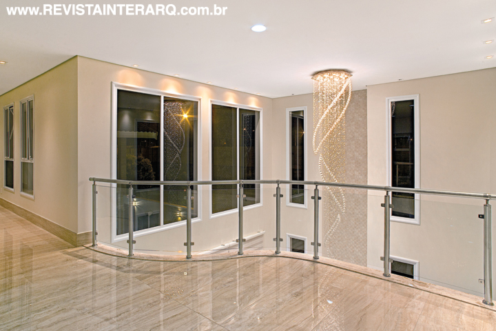 O mezanino com piso em porcelanato marmorizado (Portobello Shop) e guarda-corpo de vidro e alumínio permite admirar a delicadeza do lustre de cristais