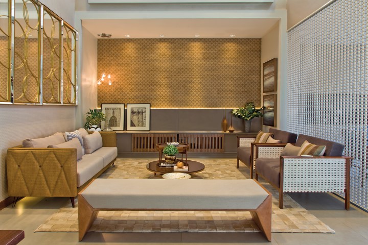 Para garantir o conforto do living com pé-direito duplo, um revestimento texturizado recobre a parede que acomoda o móvel horizontal em laca desenhado pelo escritório. A luminotécnica com luzes focais embutidas e pendente lateral valoriza as texturas. Uma cortina vazada divide sutilmente o ambiente com a varanda gourmet