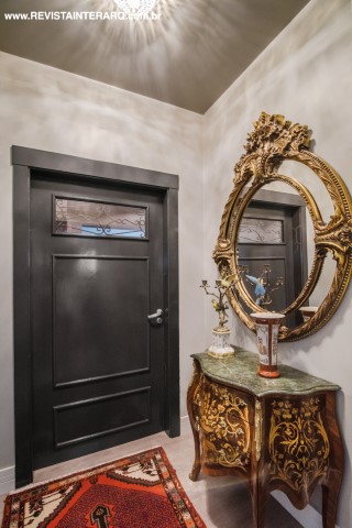 O hall do elevador exibe a porta em laca preta desenhada pela profissional e a luxuosa bombé com espelho dourado. Os tapetes Persas vermelhos são do Ateliê Revestimentos Roberto Cervellini