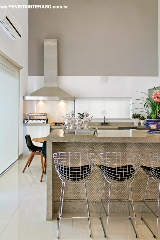 O granito Acqualux (Marmoraria São Jorge) e o revestimento da Mosarte foram as escolhas para a bancada da cozinha. Banquetas Bertoia da Perfil Casa e coifa em inox da Refrigeração Araçatuba