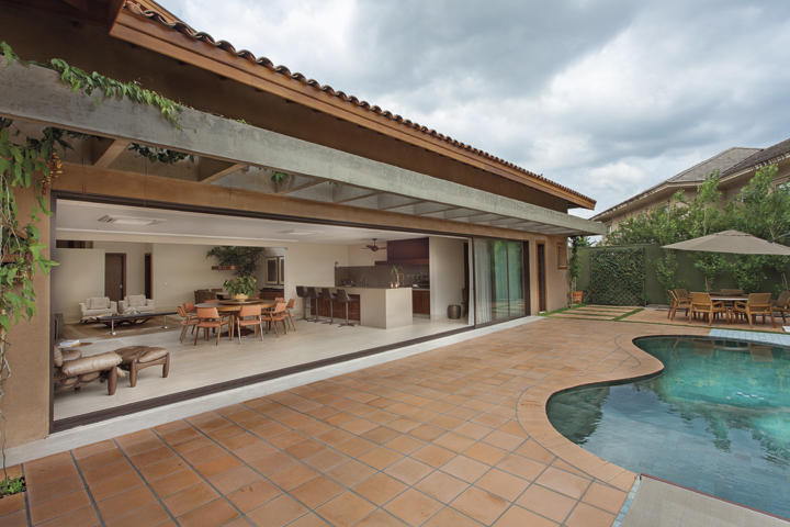A piscina de linhas sinuosas foi revestida com pedras Hijau. No entorno, cerâmicas rústicas acompanham a personalidade do telhado aparente