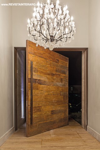 Um luxuoso lustre de cristal de rocha, desenhado por Dora Lettieri, e a iluminação embutida (Dessine) evocam luxo e receptividade no hall principal. A porta principal em madeira de demolição confere uma atmosfera de acolhimento. A casa foi toda climatizada pela Tec-lar e automatizada pela Arquitectar