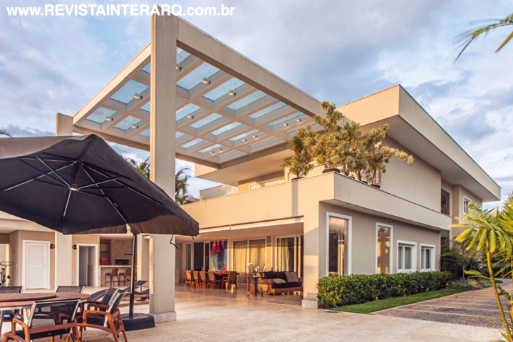 A imensa pérgola com estrutura metálica (Gravia), concreto e vidro conferiu a personalidade arrojada da fachada do lazer, posicionada em frente às águas do lago. A textura da parede (Colibri Tintas) acompanha a cor do piso em mármore Bege Bahia (Marmoraria Alvorada). O paisagismo é da Depieri