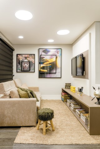 Uma sala de convívio integra o home theater e um office, que funciona como área de circulação para as duas suítes no piso superior do apartamento
