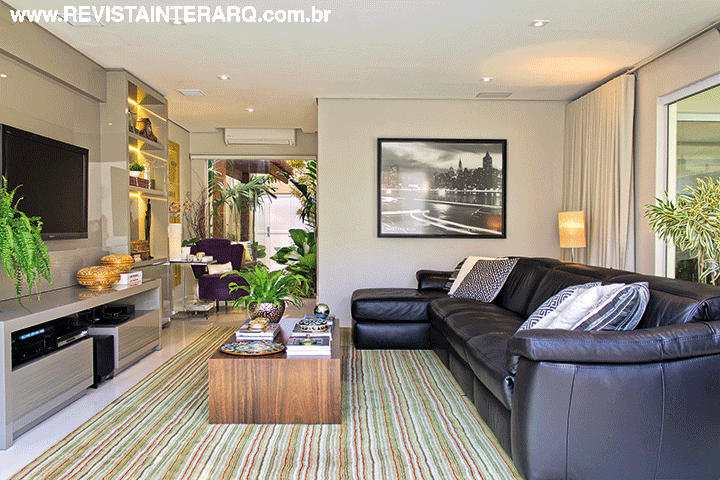 Integrado ao lazer e a um pequeno jardim, o ambiente ficou fresco e iluminado. O conforto foi garantido pelo sofá com chaises em couro da Natuzzi (Perfil Casa) e pelo tapete listrado da Avanti (Decorativa