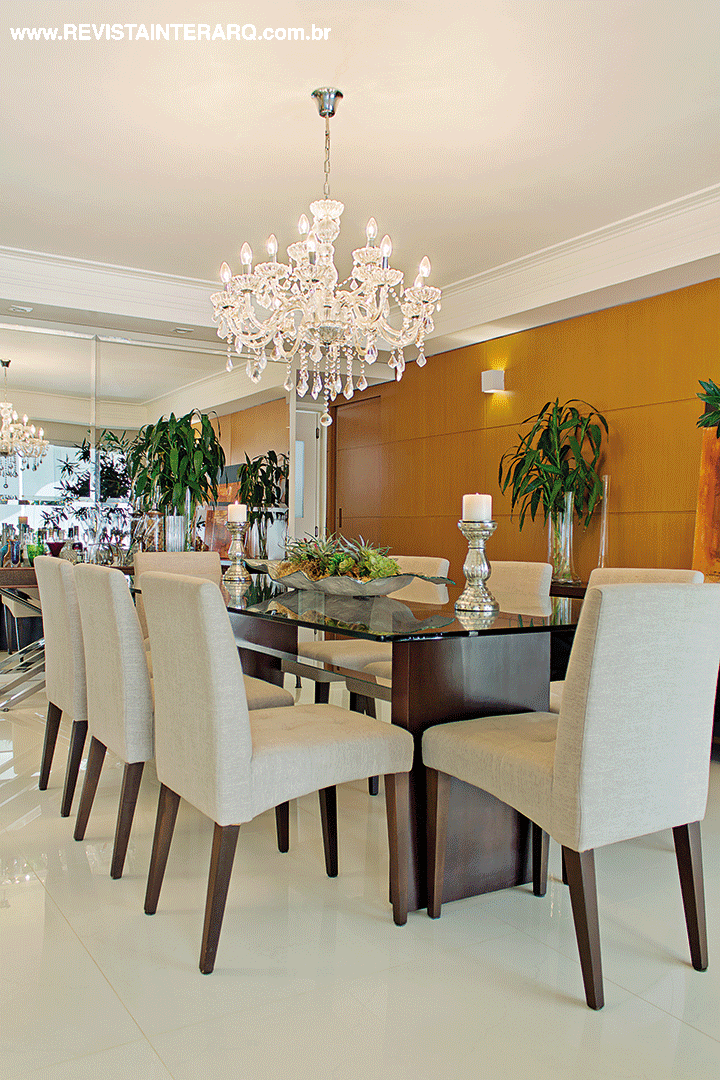 A parede espelhada (Vidraçaria Rio Preto) confere profundidade ao jantar e emoldura o móvel/bar em madeira e inox (Decorativa). O lustre de cristal clássico (NR Iluminação) faz contraponto à moderna mesa com base de madeira (GRA Móveis) e tampo de vidro (Vidraçaria Rio Preto)