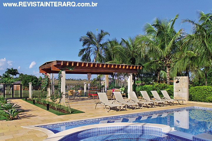 O piso de pedra São Tomé (Pedregal) do entorno da piscina se estende sob o gazebo de madeira. As chaises são da Perfil Casa. A arquitetura é de Junior Correa