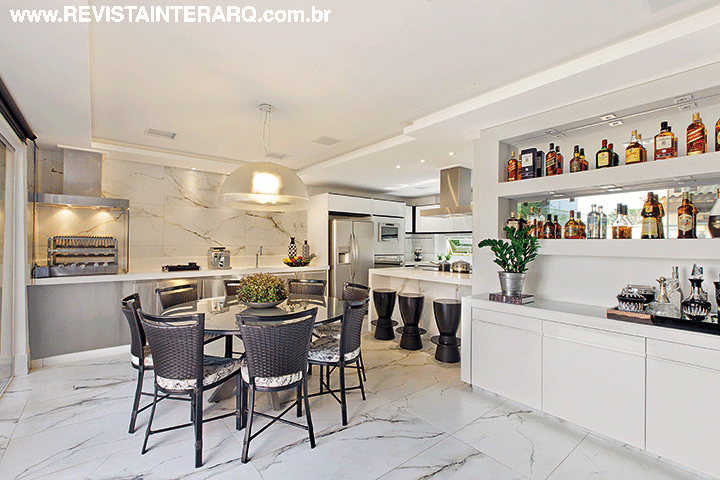 A cozinha acompanha a linguagem atemporal, com armários da Marcato, coifa da Refrigeração Araçatuba, bancada em Caesarstone (execução da Marmocruz Mármores e Granitos) e mesa da Jackie Móveis. O piso é em porcelanato da Portobello Shop
