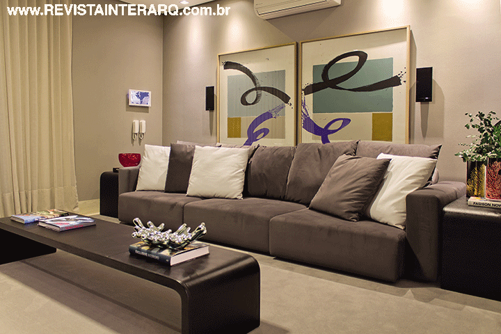 O confortável home theater, com sofá e mesas ebanizadas