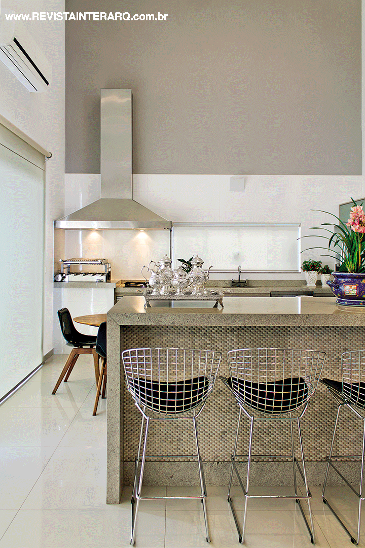 O granito Acqualux e o revestimento da Mosarte foram as escolhas para a bancada da cozinha. Banquetas Bertoia da Perfil Casa, persiana Hunter Douglas da Griffe A e coifa em inox da Refrigeração Araçatuba