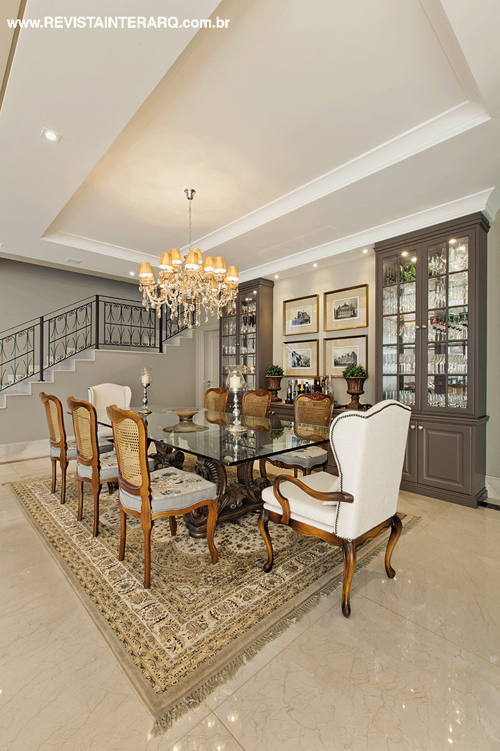 As cristaleiras desenhadas pelas profissionais acomodam as taças sem ocupar muito espaço na sala de jantar. Herança de família, a mesa de vidro completa a cena com cadeiras com encosto de palhinha, poltronas estofadas (Sierra Perfil Casa), tapete oriental e lustre clássico