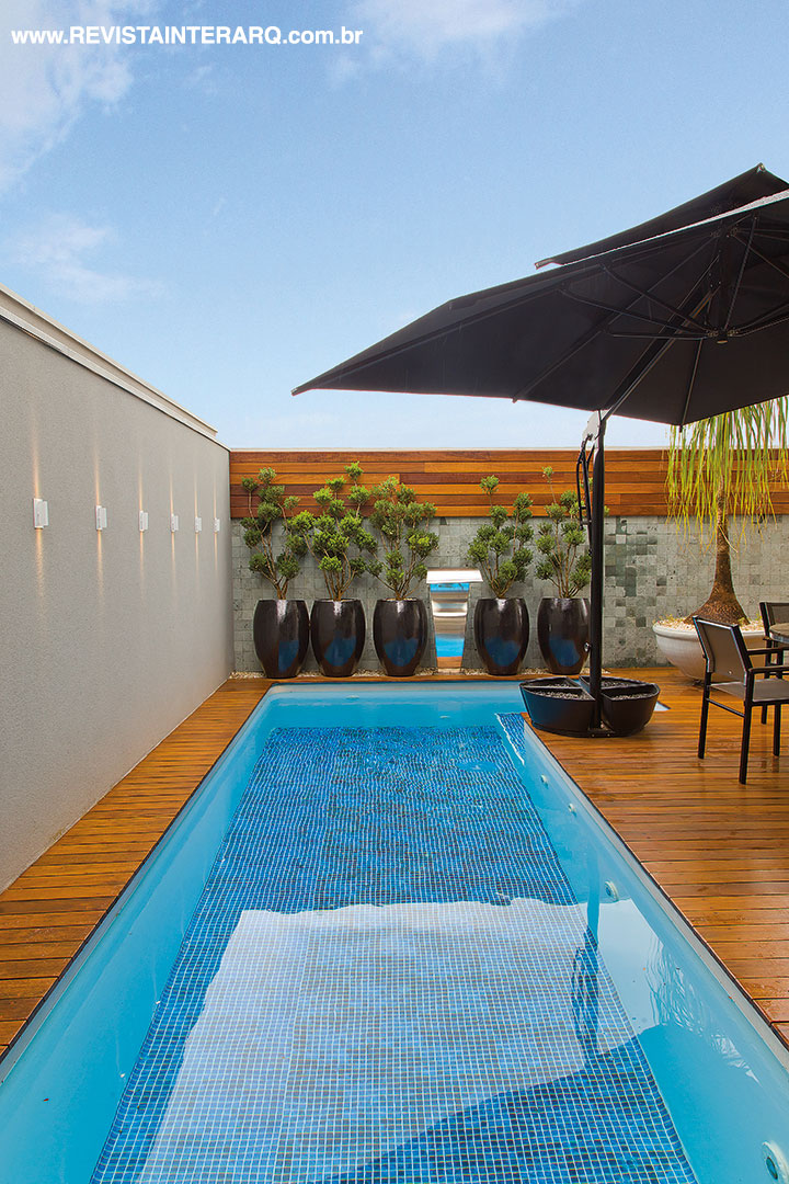 O painel de madeira (Marcello Revestimentos) conferiu aconchego à área da piscina em forma de raia e com cascata em inox (Vulcano Lazer e Cia). No deck, a opção foi por móveis resistentes às intempéries. Na parede, revestimento em pedras Hijau
