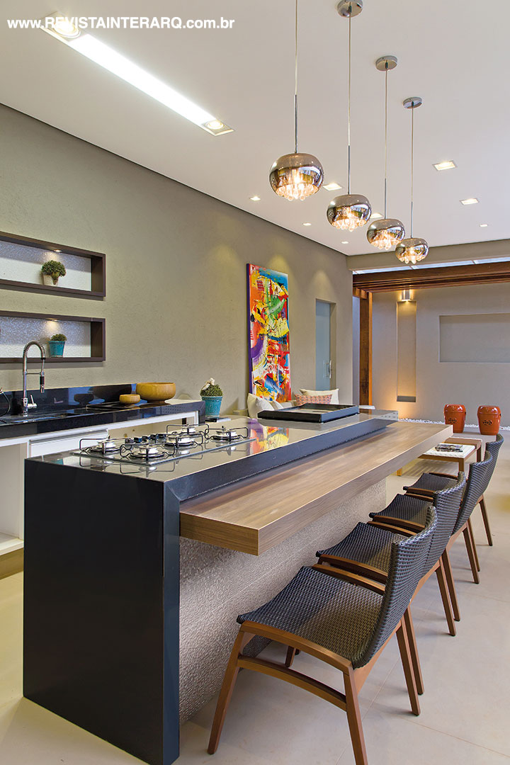 Na varanda gourmet a iluminação destaca a tela colorida (Galeria Top Kazza | Saccaro) e peças decorativas em nichos de madeira sobre a bancada