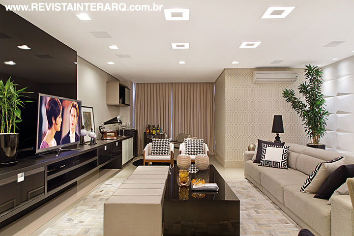 A ambientação do living foi marcada pelas luminárias rebatedoras embutidas no espaço de TV e pelas luzes pontuais que valorizam o painel com revestimentos em alto relevo (Ponto Bello Acabamentos). O móvel planejado é da Todeschini e as almofadas, poltronas e quadros, da Stylo & Classe