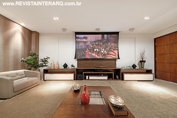 O home theater automatizado e com projetor conta com acústica favorecida pelos papéis de parede, cortinas e tapete de medidas generosas