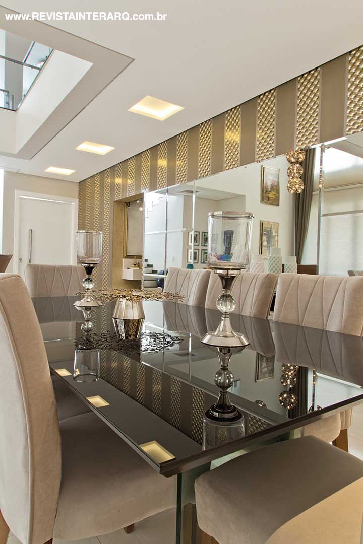 No espaço do jantar, o espelho com detalhes bisotês duplica visualmente a mesa em laca preta e a iluminação direcionada (Reflexo Iluminação). As poltronas em madeira e couro, mesas laterais e de centro são da Galeria Top Kazza | Saccaro