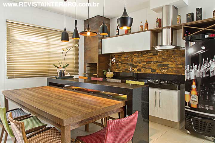 Na varanda gourmet, o painel com mosaico de pedra ferro compõe com o revestimento da churrasqueira em porcelanato Aço Corten