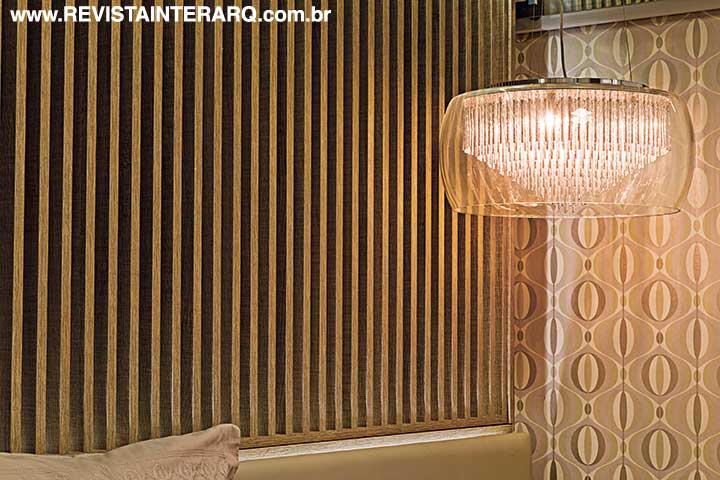 Estampas, texturas dos papéis de parede e o lustre sobre o criado-mudo são destaques na composição, trabalhada com cores sóbrias e aconchegantes