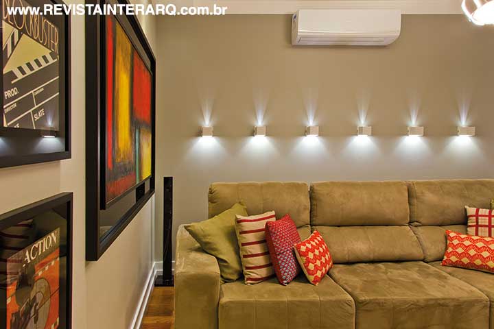No home-theater, a iluminação cênica (Reflexo Iluminação) valoriza o painel da TV e a parede atrás do sofá