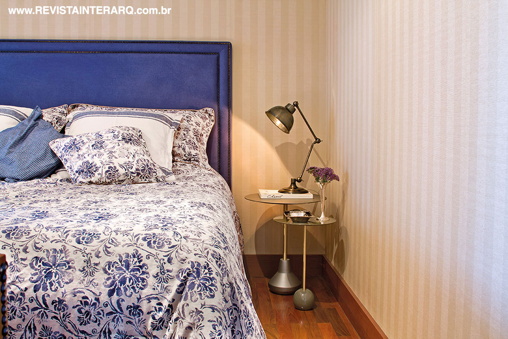 A suíte do casal, o papel de parede em palha ressalta a cabeceira em linho azul da Entreposto (Jackie Móveis). Mesas laterais da Perfil Casa e enxoval Ralph Lauren