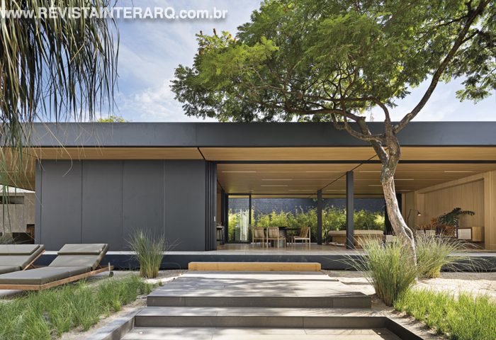 A casa projetada por Arthur Casas utiliza sistema pré-fabricado modular, que permite erguer toda a estrutura em poucos dias, praticamente sem resíduos e sem água, utilizando matérias-primas 100% recicláveis. A casa possui mecanismos de captação e reúso de água da chuva, energia solar por meio de painéis fotovoltaicos e biodigestor, que transforma lixo orgânico em gás para o uso na cozinha e lareira. Uma cobertura verde no telhado contribui para o conforto térmico e acústico. O paisagismo de Renata Tilli tem espécies que se adaptam ao clima de qualquer região. Foto: Filippo Bamberghi