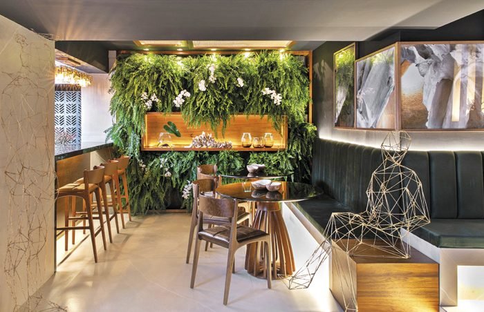 Inspirados nos tons pretos do mármore Nero, o Nero Café, desenvolvido por Hélio Ribeiro e Priscilla Marchetto, possui bases e bancadas inspiradas nesta referência e destacam o belo jardim vertical composto por samambaias e orquídeas.
